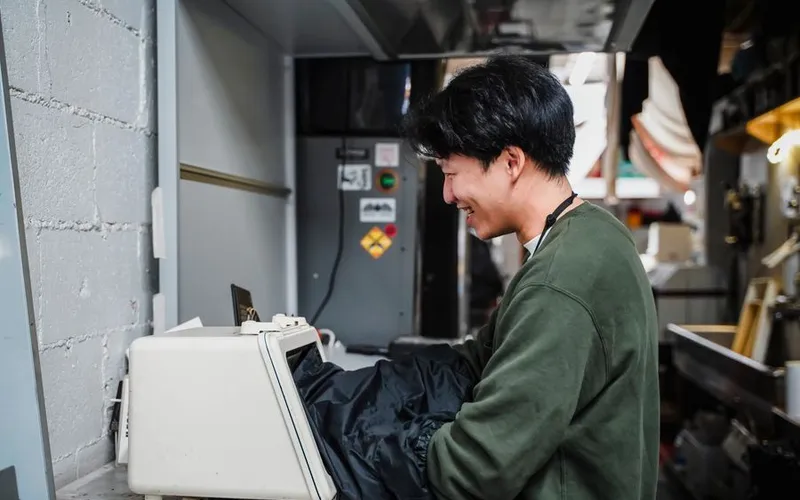A young machinist smiling as he checks a part