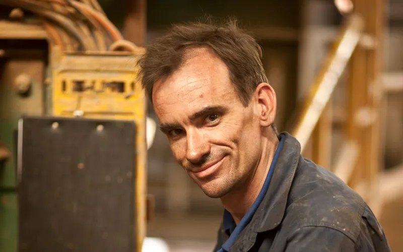 A machinist smiling at his machine control